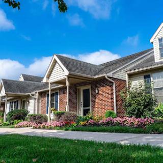 A charming residential building with a well-maintained garden and vibrant flowers under a clear blue sky.