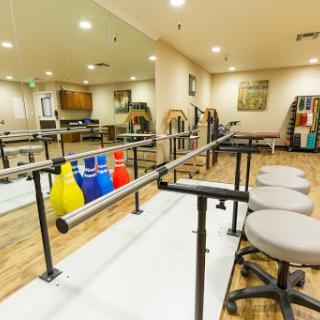 A well-equipped physical therapy room featuring walking bars and exercise tools for rehabilitation.