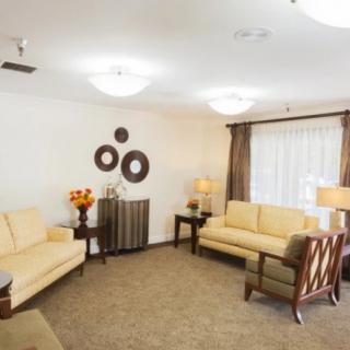 A cozy living room with beige sofas, decorative elements on the wall, and warm lighting.