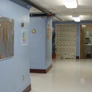 An empty hospital hallway with blue walls and fluorescent lighting.