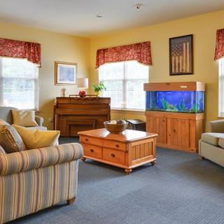 A cozy living room with comfortable seating, a wooden coffee table, an aquarium, and a piano.