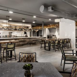 A modern restaurant interior with an industrial design, featuring a spacious bar area and stylish seating arrangements.