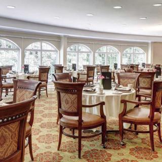 An elegant restaurant dining area with arranged tables and chairs, featuring large windows.