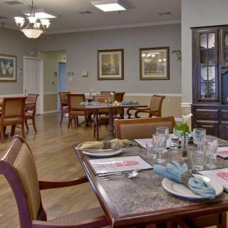 A neatly arranged dining room with elegantly set tables and a chandelier overhead.
