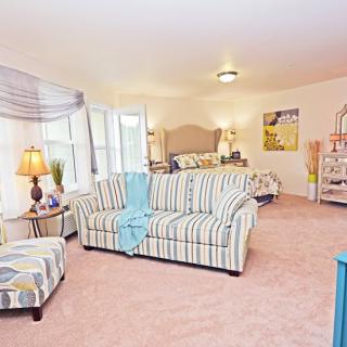 A cozy living space featuring a striped sofa and a bed in an open-concept room.