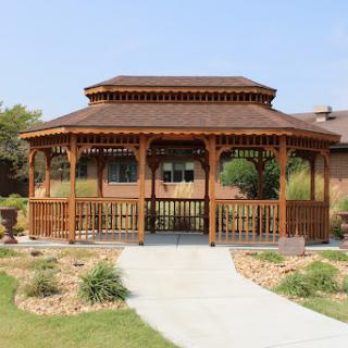 A beautifully designed wooden gazebo in a well-maintained garden, providing a serene outdoor space.