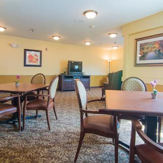 A cozy dining area with tables and chairs, a television, and framed artwork on the walls.