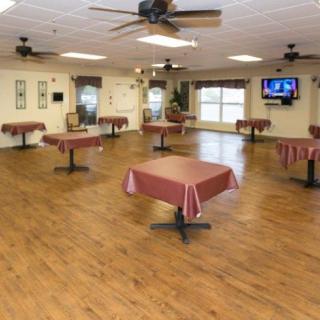 An empty dining room with tables and ceiling fans, featuring a wooden floor.