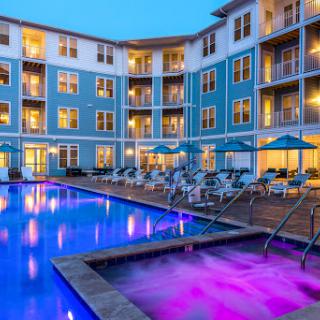 A luxurious hotel featuring a vibrant swimming pool and inviting outdoor lounges, perfect for an evening retreat.
