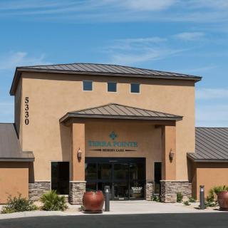 A commercial building with a central entrance and decorative planters outside, set against a clear sky.