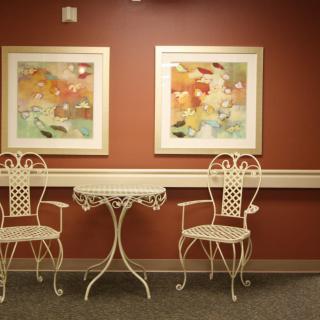 A cozy seating area with two decorative chairs and a small table, adorned with colorful artwork on the wall.