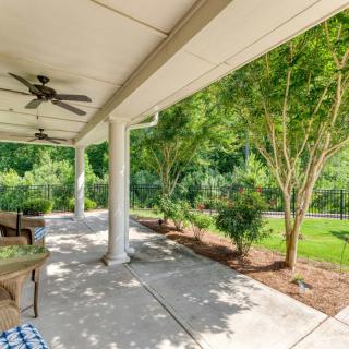 A bright and relaxing patio with ceiling fans, surrounded by lush greenery.