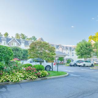 A residential building with well-maintained landscaping and parked cars in the foreground.