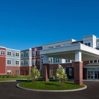 A modern residential building with a landscaped entrance and clear blue skies.