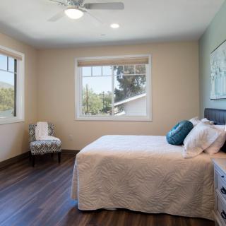 A bright and cozy bedroom with a large bed, hardwood floors, and ample natural light streaming through the windows.