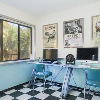 A retro-styled office space featuring vintage posters, a checkered floor, and computers on a sleek desk.