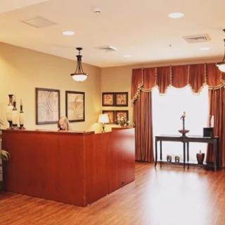 A warmly lit reception area with a wooden desk and elegant decor.
