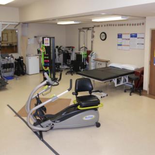 A therapy room equipped with an exercise bike and various rehabilitation equipment.