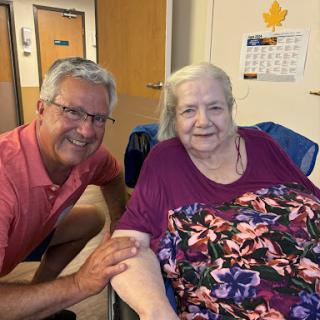 A joyful moment shared between a caregiver and an elderly individual, both smiling warmly.