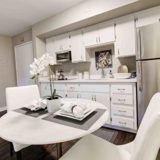 A modern kitchen with white cabinetry and a sleek dining table.