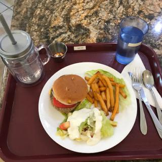 A delicious meal featuring a burger, sweet potato fries, and a fresh salad served on a tray.