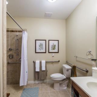 A clean and modern bathroom featuring a shower, toilet, and sink with light decor.