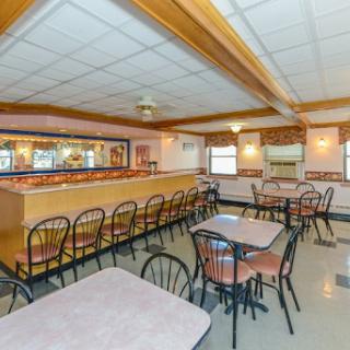 A cozy dining area featuring multiple tables and chairs, with a bar in the background.