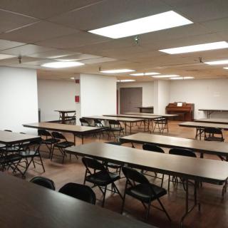 An empty conference room with several tables and chairs arranged for a meeting.