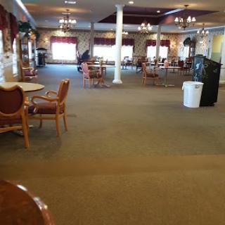 A spacious dining area featuring empty tables and chairs, illuminated by soft lighting.