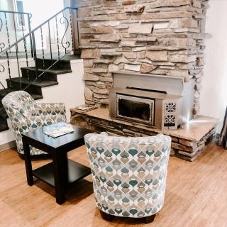 A cozy living room with patterned armchairs and a stone fireplace.