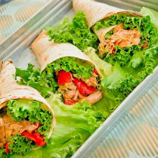 Three fresh vegetable wraps with lettuce and red peppers.