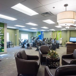 A modern fitness center with cardio machines and a comfortable seating area.