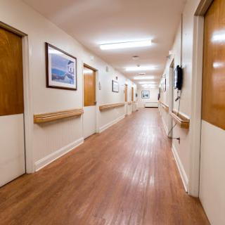 A well-lit hospital hallway with wooden doors and framed artwork.