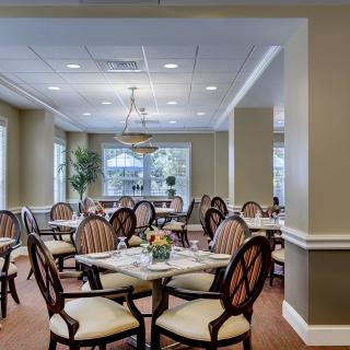 A well-lit dining room with elegantly arranged chairs and tables.