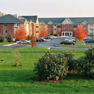 A picturesque view of a residential building surrounded by autumn foliage and a well-maintained lawn.