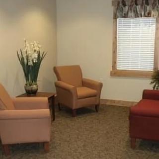 A cozy waiting room with comfortable chairs and a potted plant near the window.