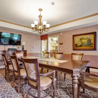 A well-appointed dining room featuring a large table, elegant chairs, a chandelier, and a mounted television.