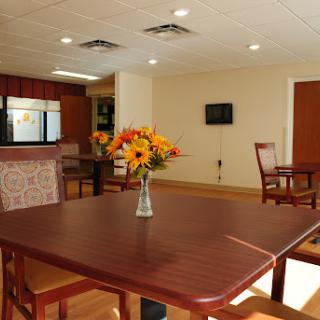 A cozy dining area featuring a wooden table with flowers and comfortable seating.