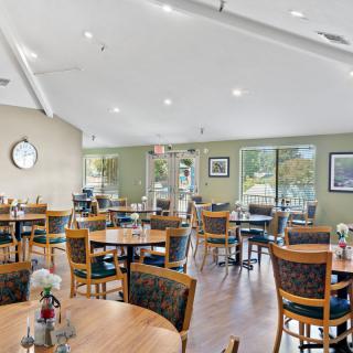 An indoor dining area with neatly arranged tables and chairs, decorated with flowers.