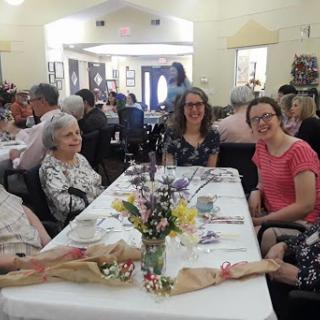 A joyful gathering around a beautifully set table, filled with flowers and surrounded by loved ones.