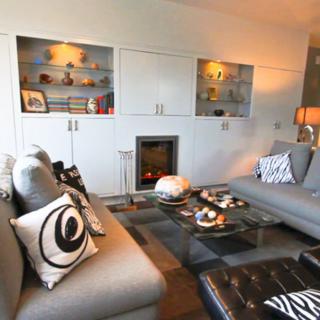 A modern living room with stylish decor, featuring two large sofas, a glass coffee table, and built-in shelves.