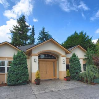 A picturesque residential house with a driveway and lush greenery.