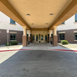 The entrance of a modern building featuring an inviting canopy and landscaped surroundings.