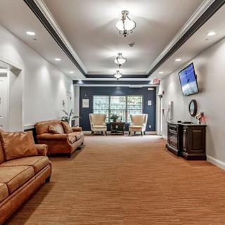 A well-lit lobby area featuring comfortable sofas, decor, and a wall-mounted television.