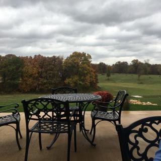 A patio set overlooking a grassy landscape with trees and a cloudy sky.