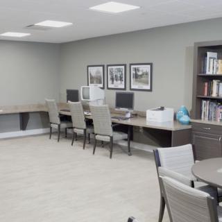 A modern office space with multiple workstations and a bookshelf.