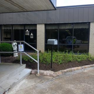 A view of the entrance to a building featuring landscaped areas and a mailbox.