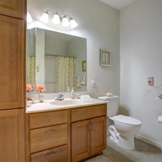 A well-lit bathroom featuring a wooden vanity, sink, and toilet.