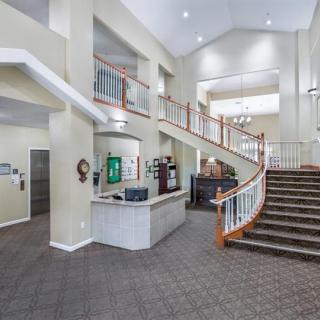 A spacious and modern lobby featuring a reception desk and a grand staircase.