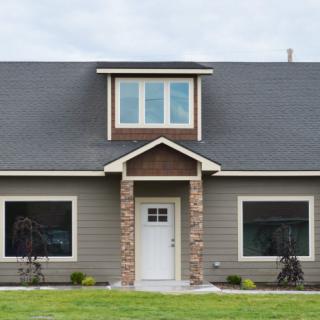 A modern residential house with a front lawn and two large windows.
